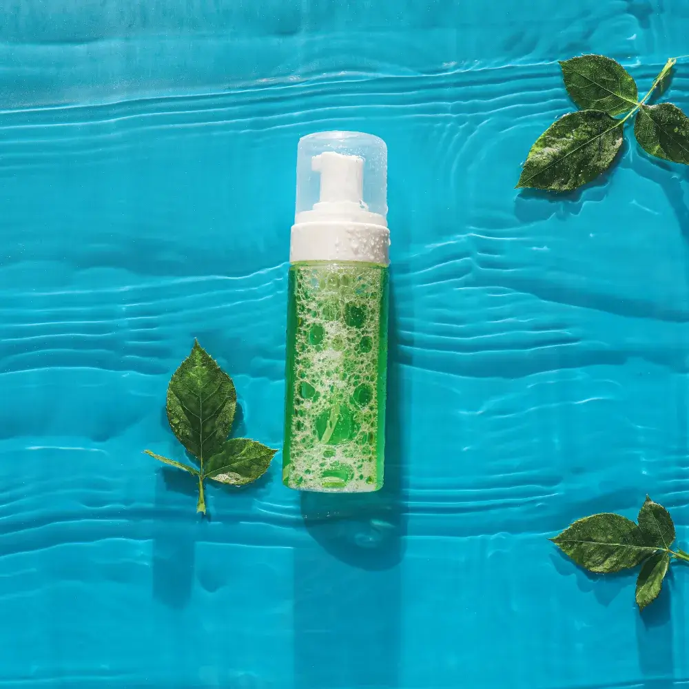green face wash bottle placed on the water with leaves