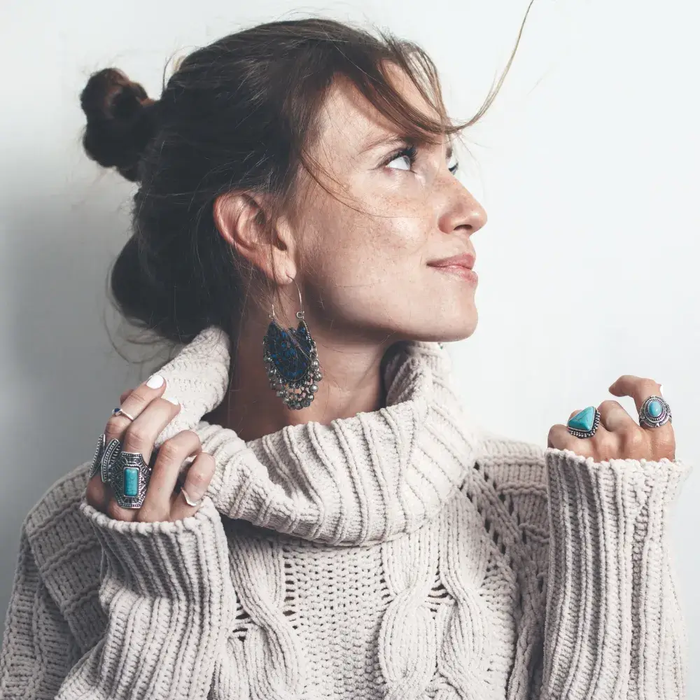 side view portrait of a woman wearing boho earrings and rings