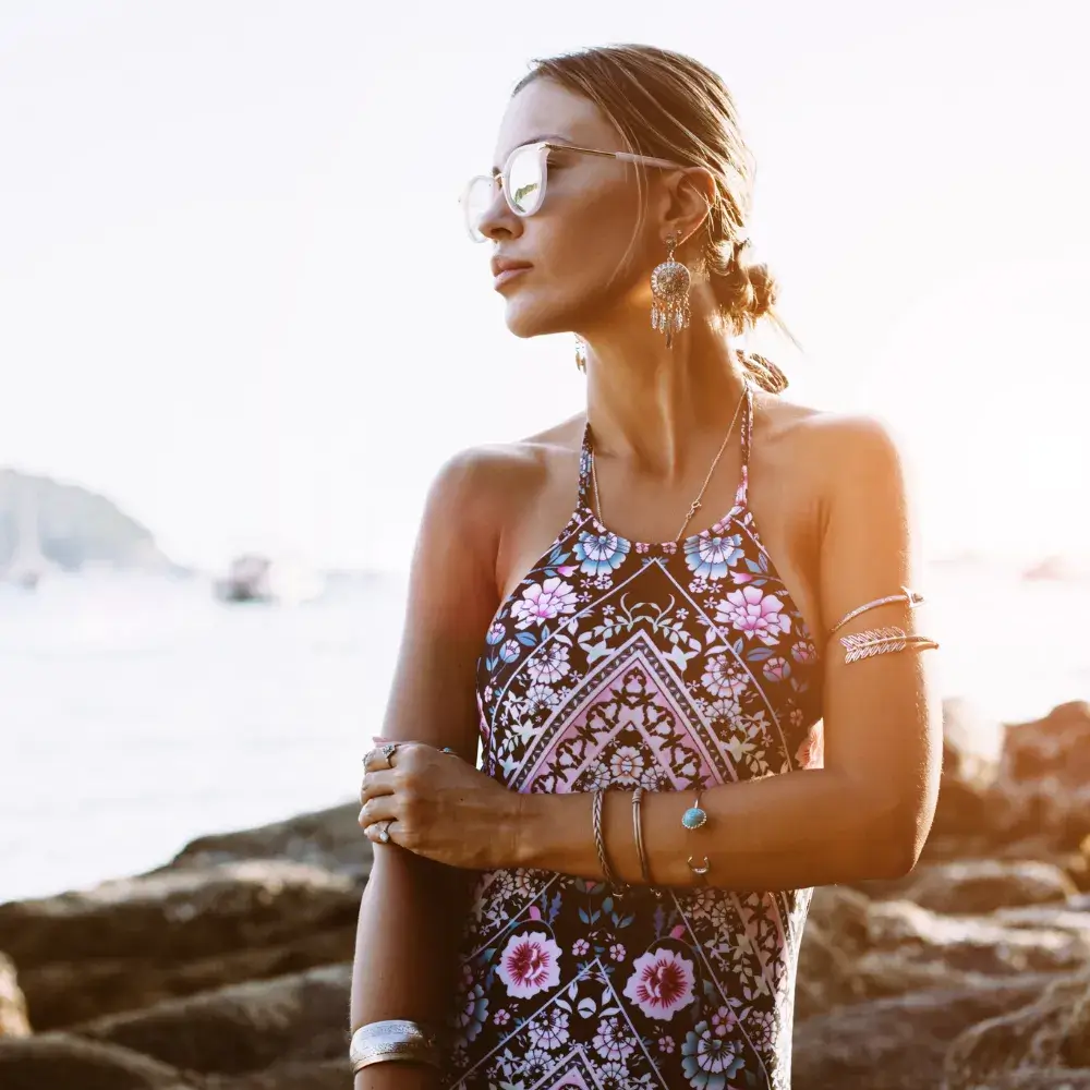 A woman in ethnic swimwear and sunglasses is adorned with boho jewelry