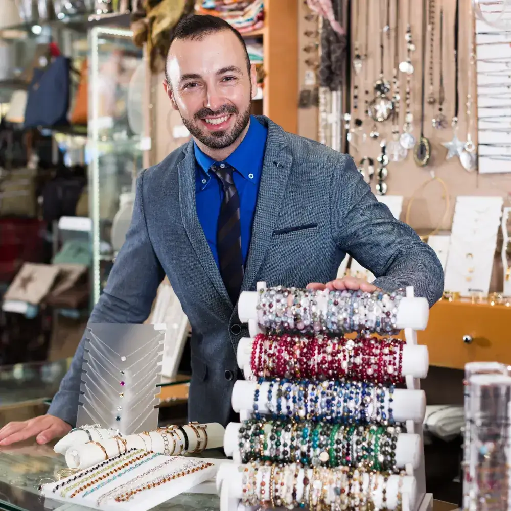 smiling man in a suit selling different types and colors of bracelets