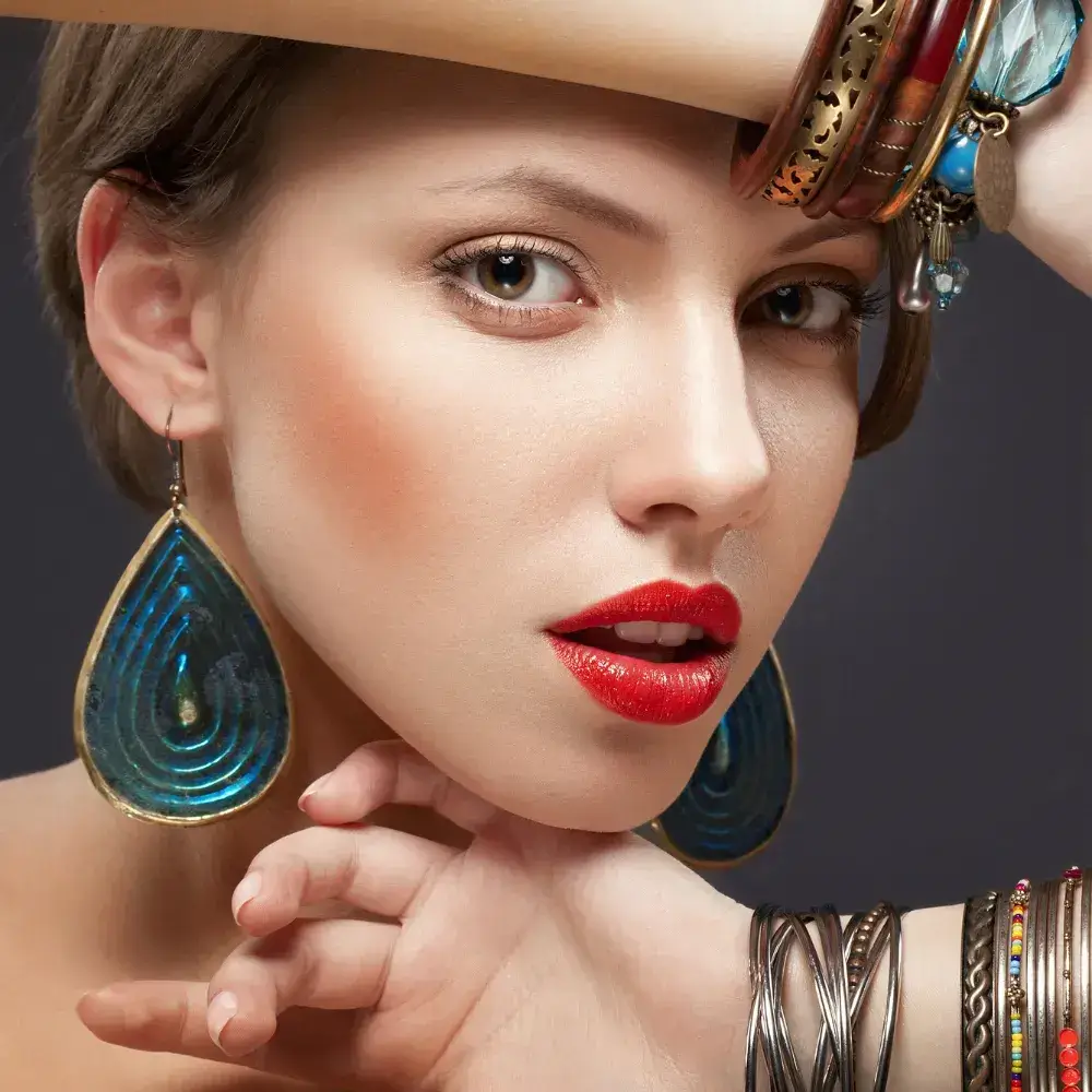 portrait of a woman with red lipstick wearing dangling earrings and colorful bracelets